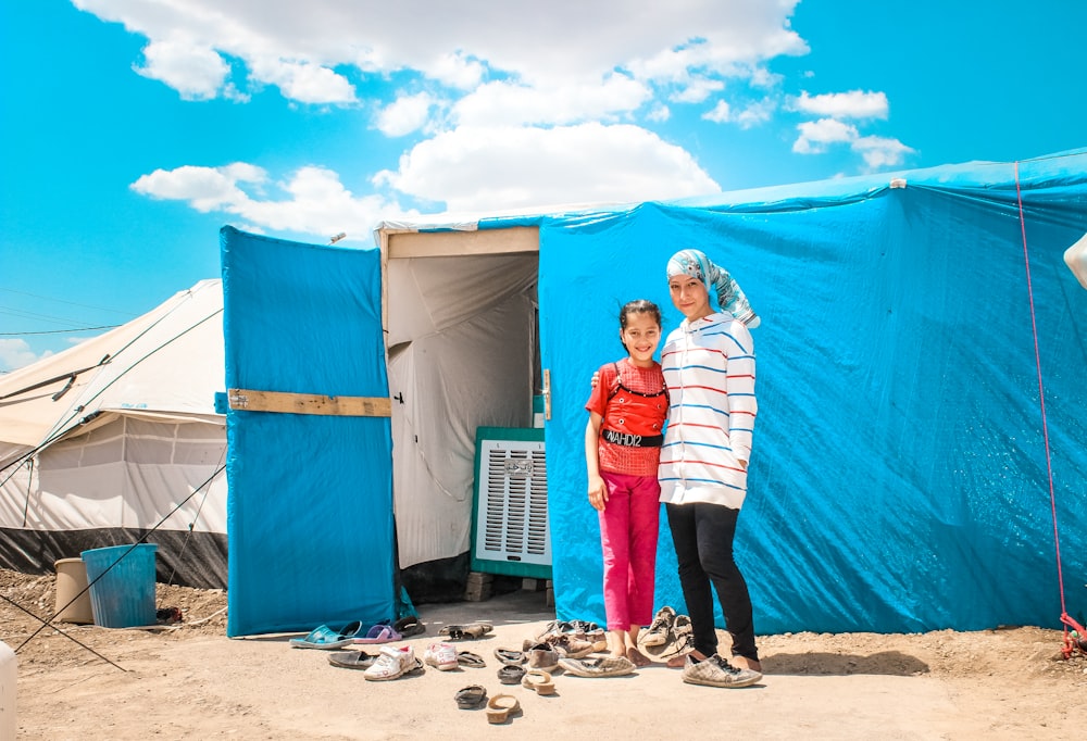 two women standing in front of a blue tent