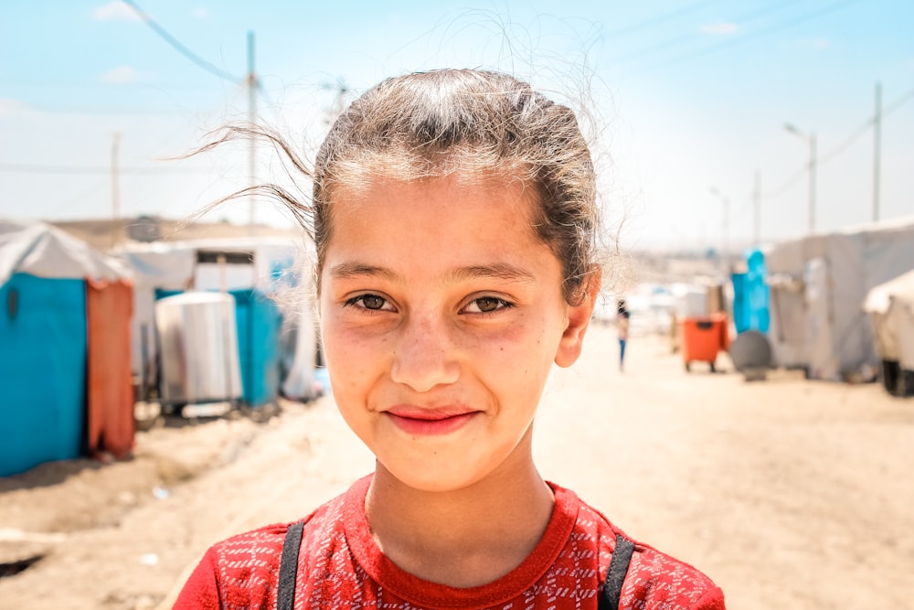 a young girl standing in front of a dirt road