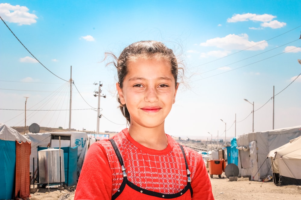 a young girl standing in front of a group of tents