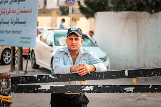 a man leaning on a fence in front of a car