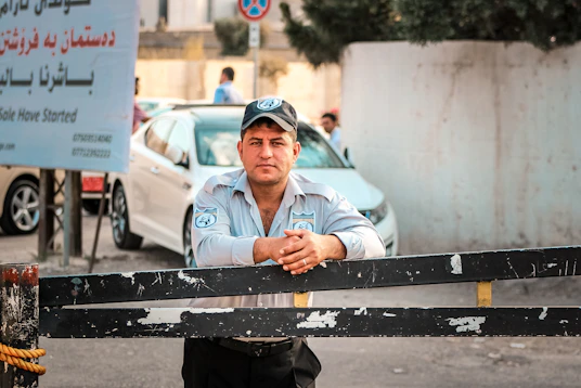 a man leaning on a fence in front of a car