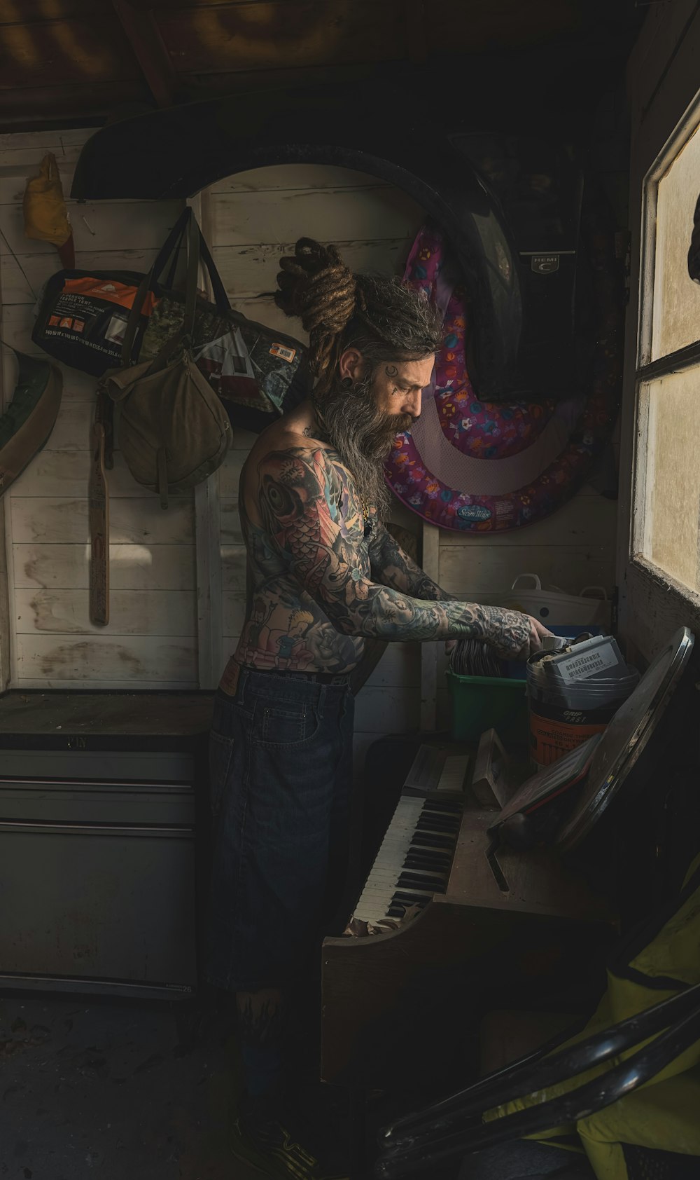 a tattooed man playing a piano in a garage