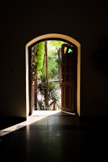 an open door leading into a lush green garden