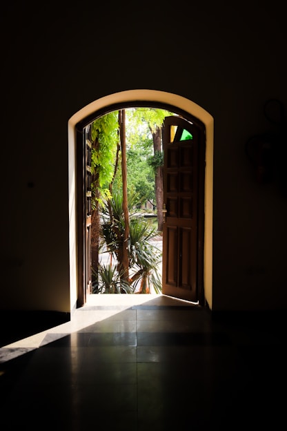 an open door leading into a lush green garden