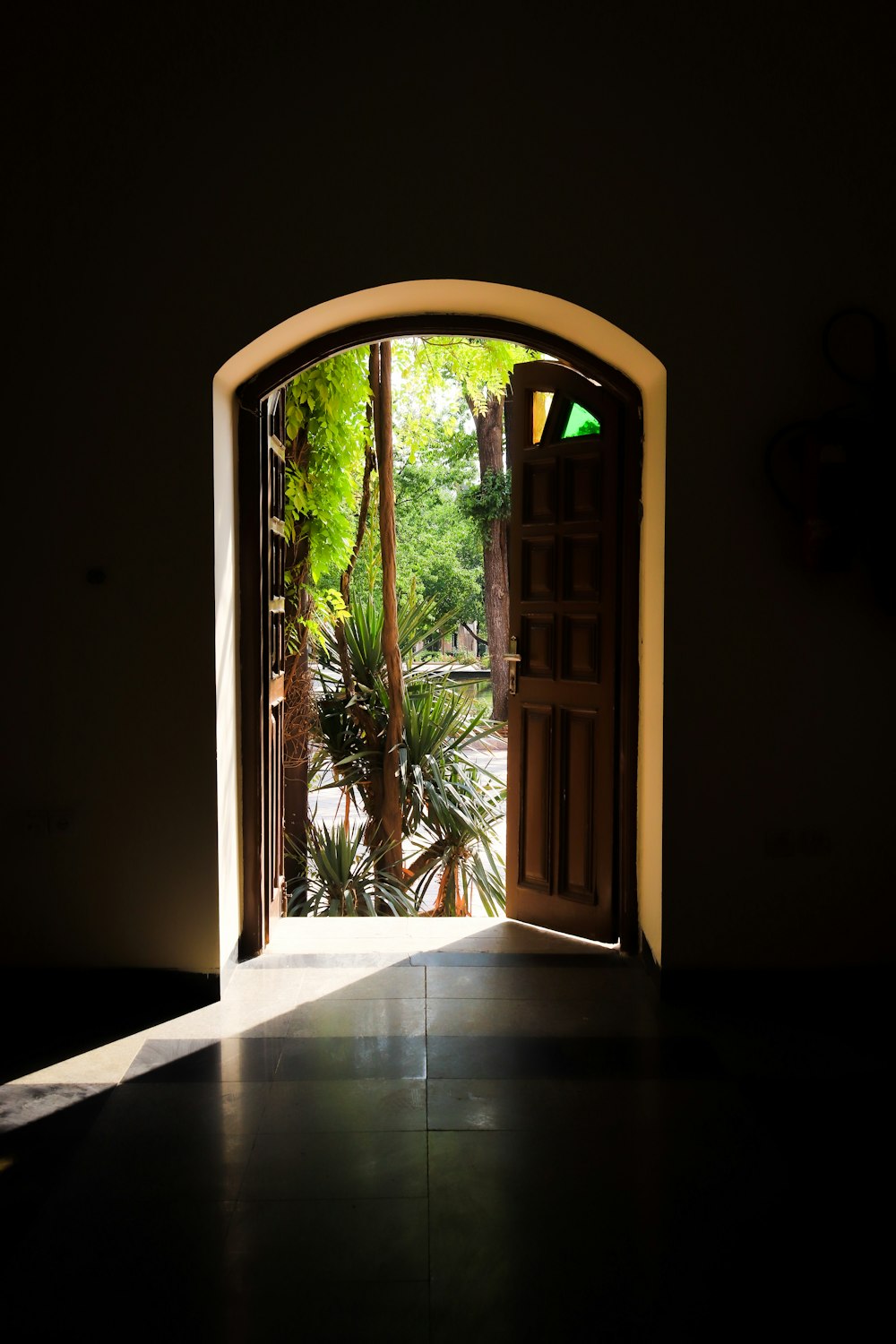 an open door leading into a lush green garden