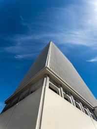 A sleek, modern building under construction with clean lines and a gray-black color scheme against a clear sky.