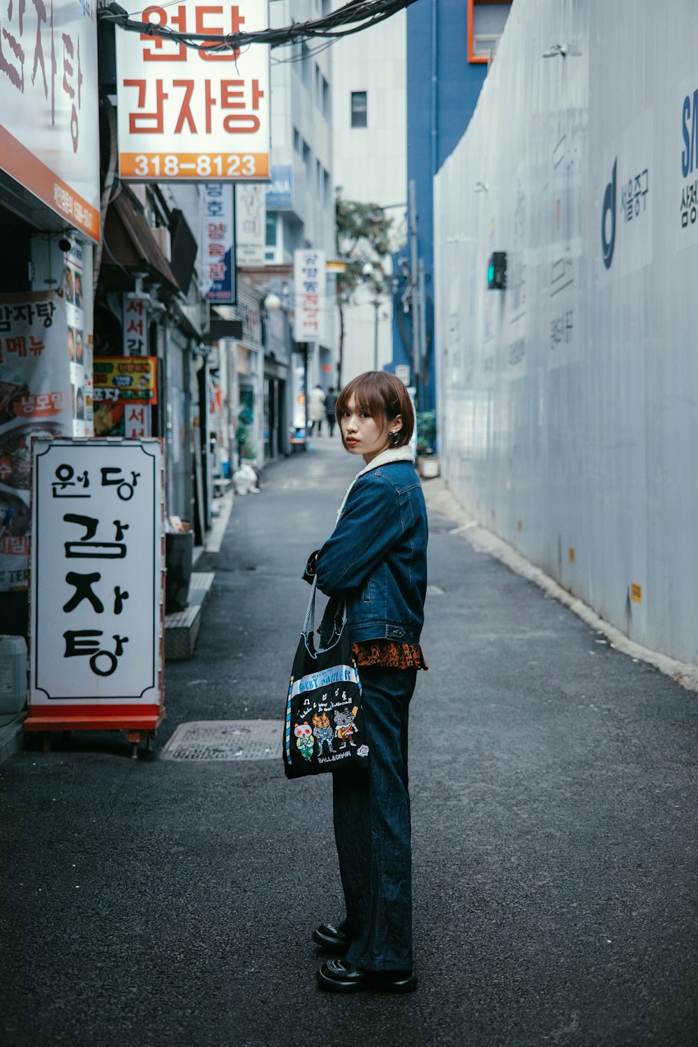 a boy standing on a street holding a bag