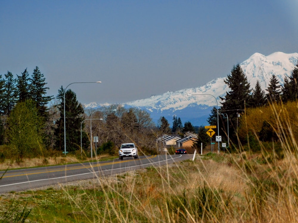 a car driving down a road with a mountain in the background