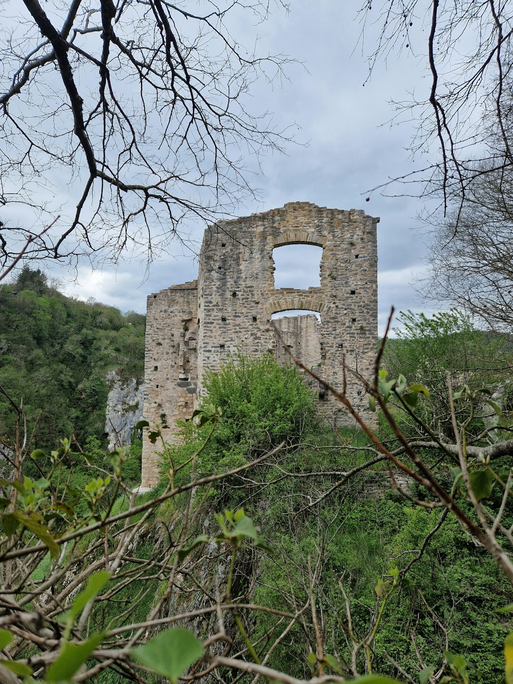 a stone building sitting on top of a lush green forest