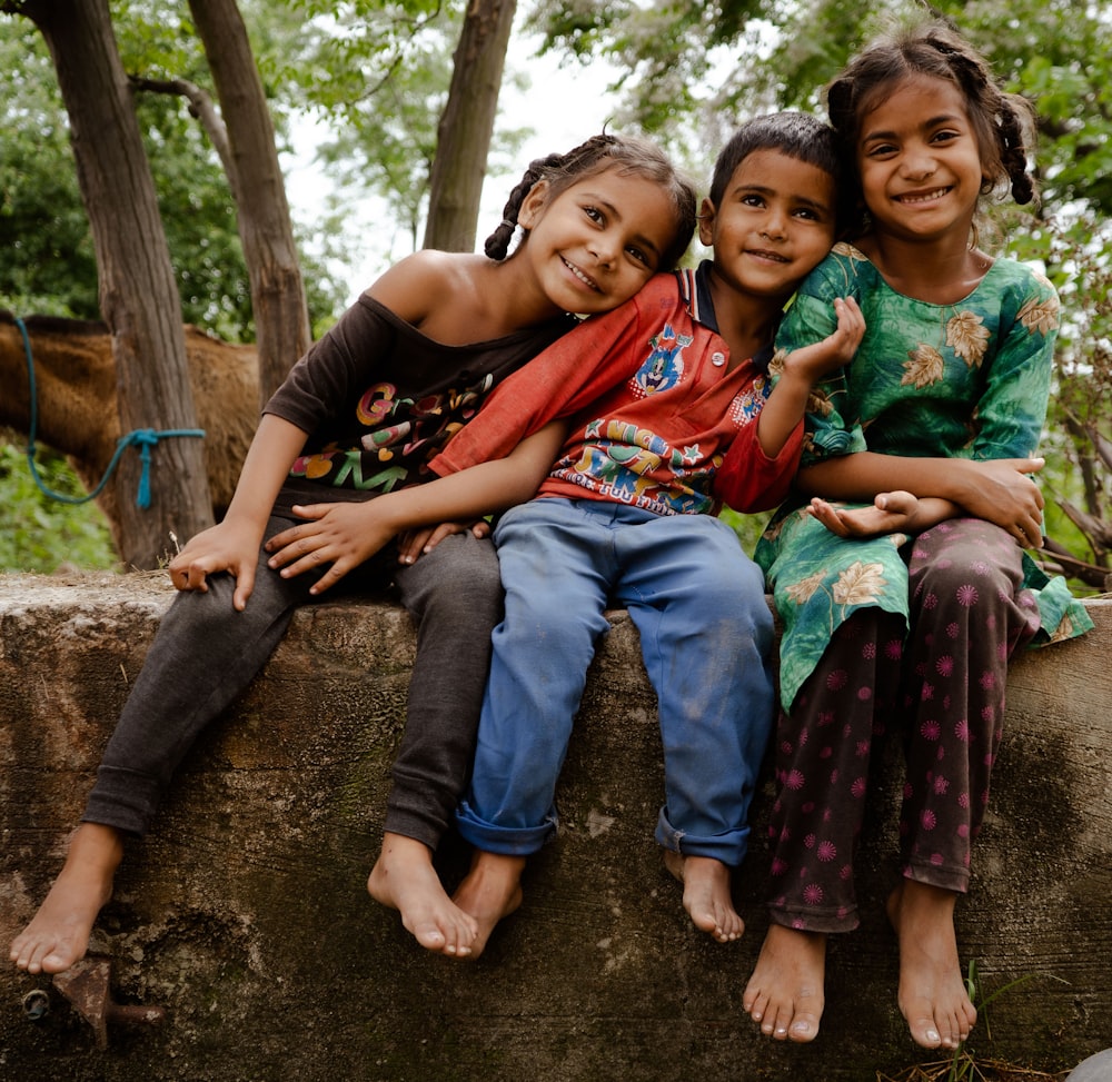 three young girls sitting on a stone wall