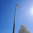 Hands carefully assembling a flagpole outdoors with sunlight filtering through trees.