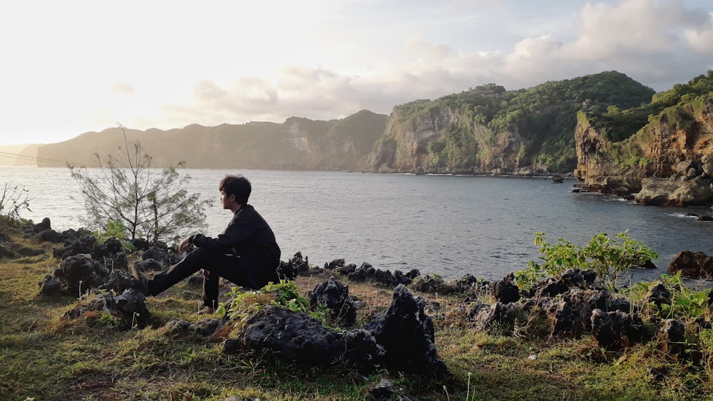 a person sitting on a hill overlooking a body of water