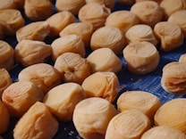 A collection of dried apricots spread out on a blue mesh surface, capturing their textured and wrinkled appearance. The light creates subtle shadows that highlight their natural shapes.