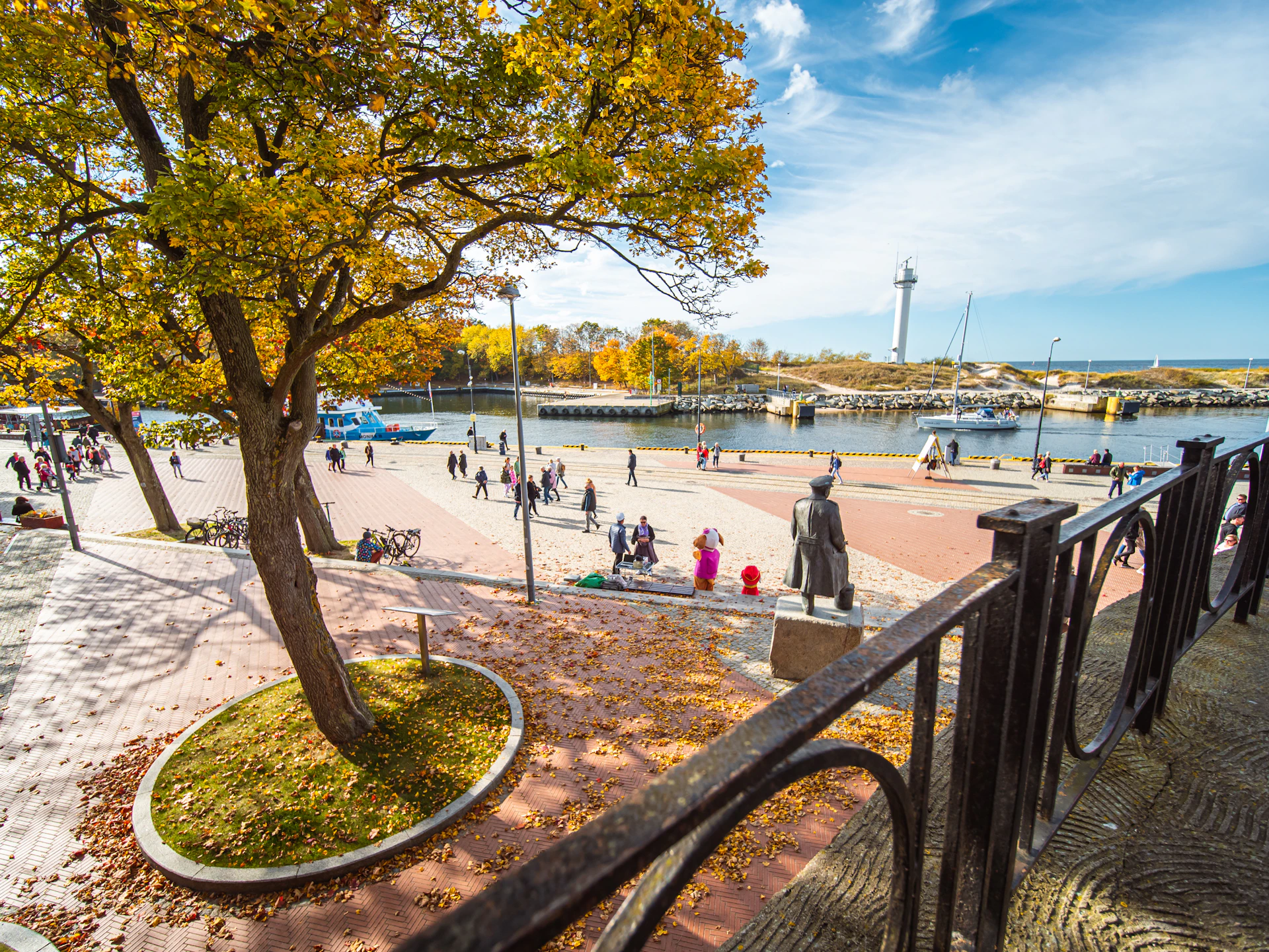 a group of people walking around a park next to a river