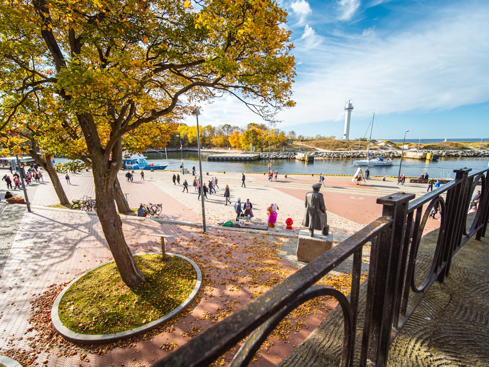 a group of people walking around a park next to a river