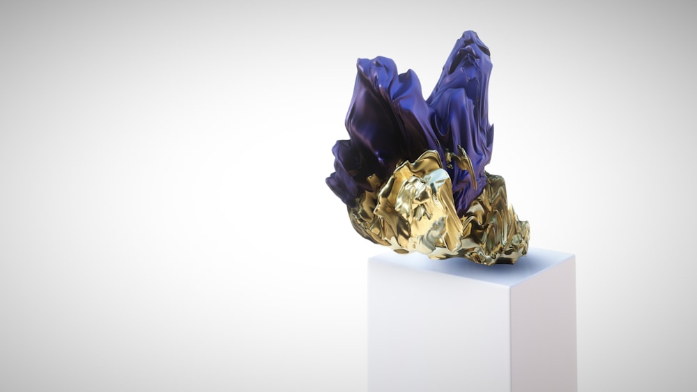 a gold and purple sculpture sitting on top of a white block