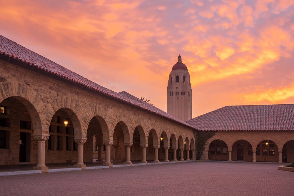 a building with arches and a clock tower in the background