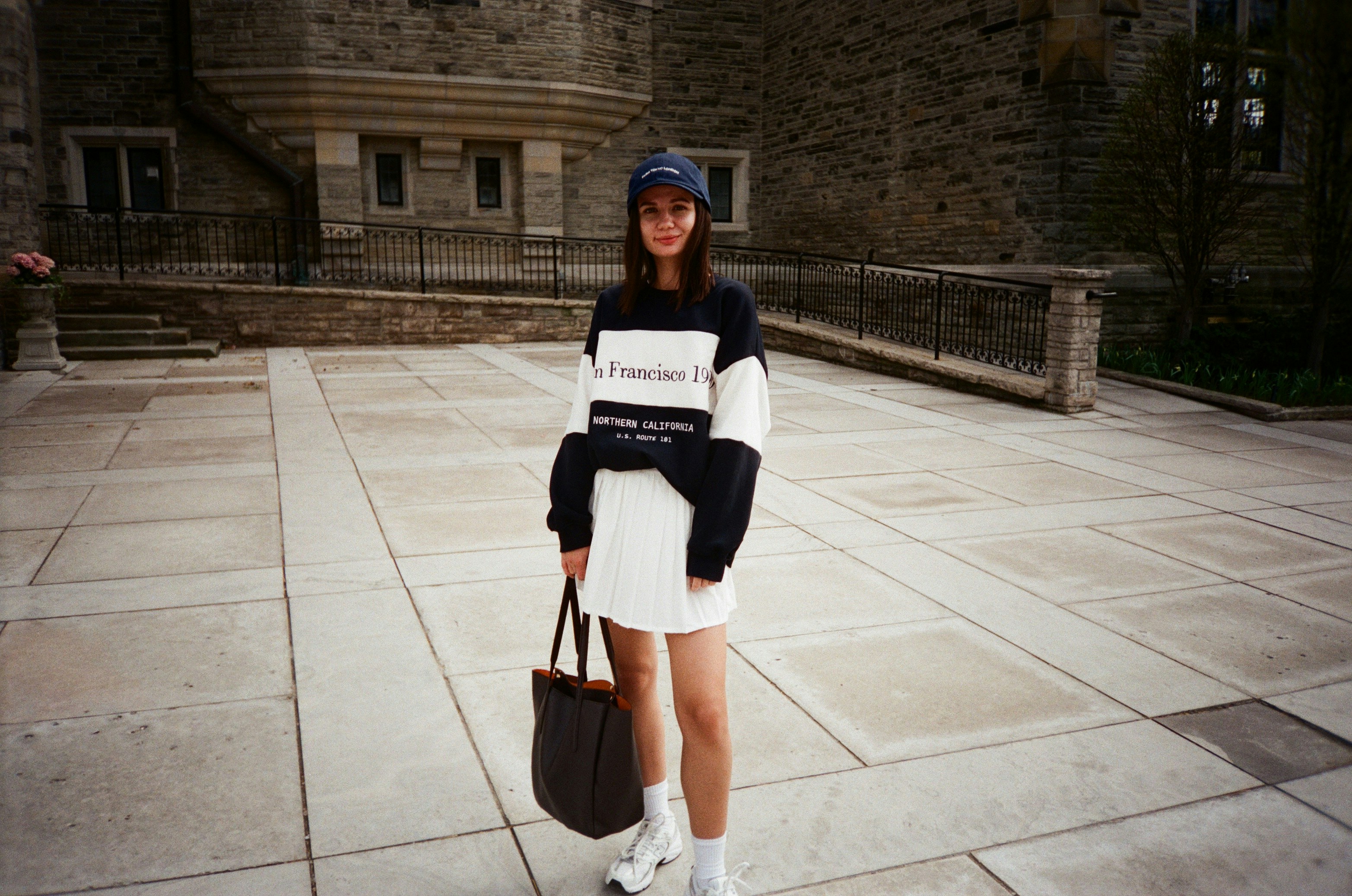 a woman standing on a sidewalk holding a purse