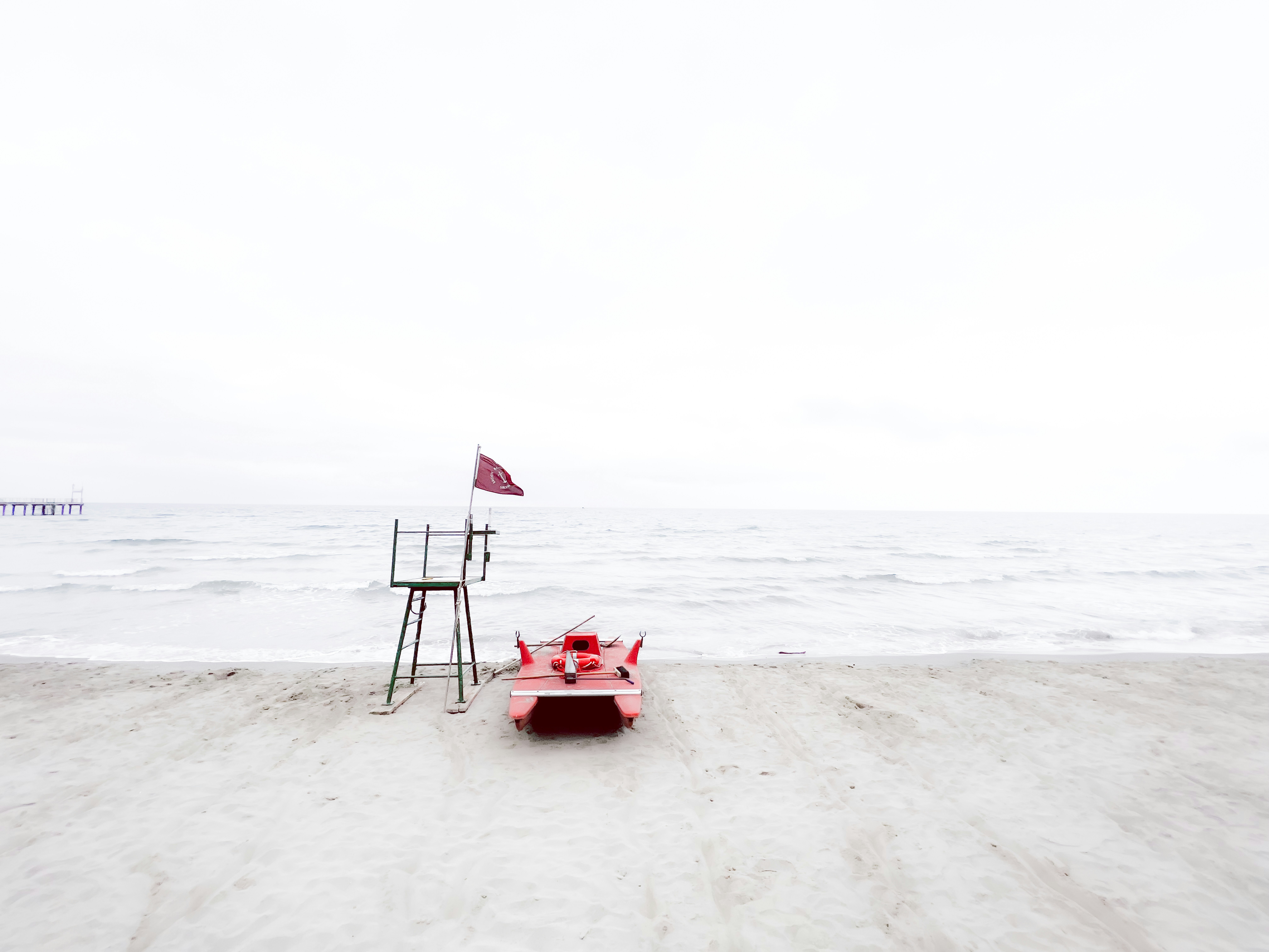 A red bench sitting on top of a sandy beach