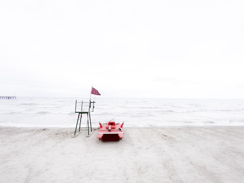 Un banco rojo sentado en la parte superior de una playa de arena