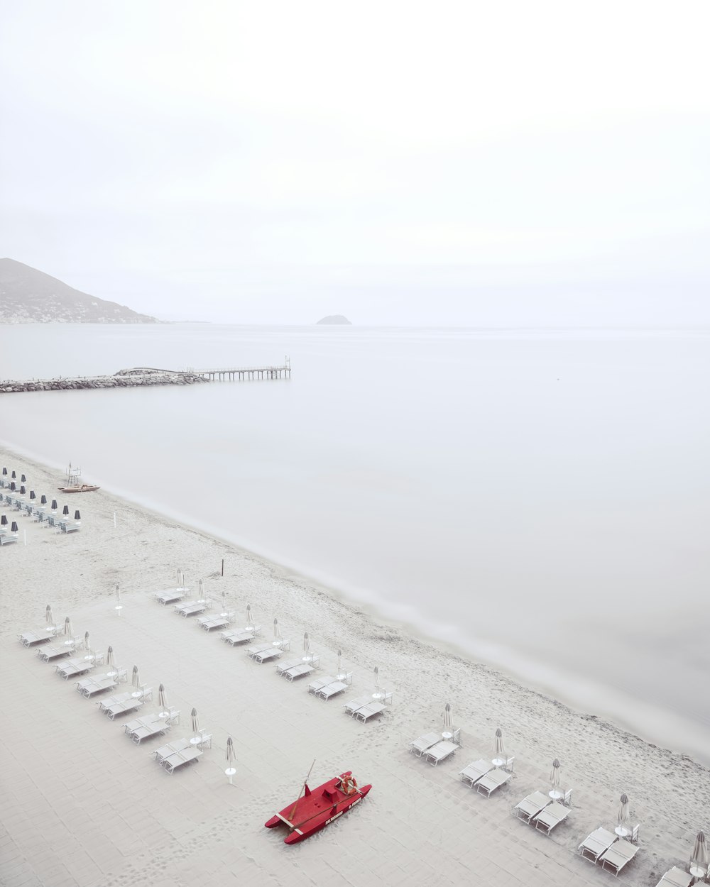 a red umbrella sitting on top of a sandy beach