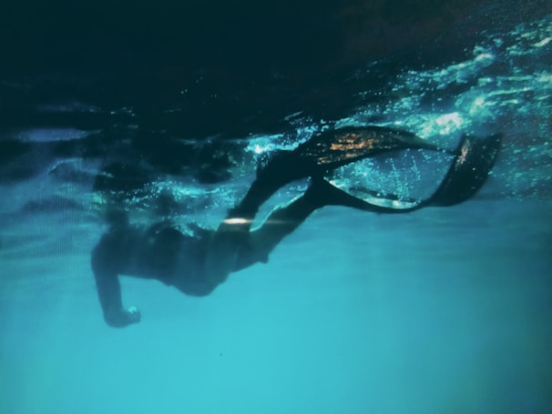 Swimmer practicing underwater dolphin kicks with bubbles trailing behind.