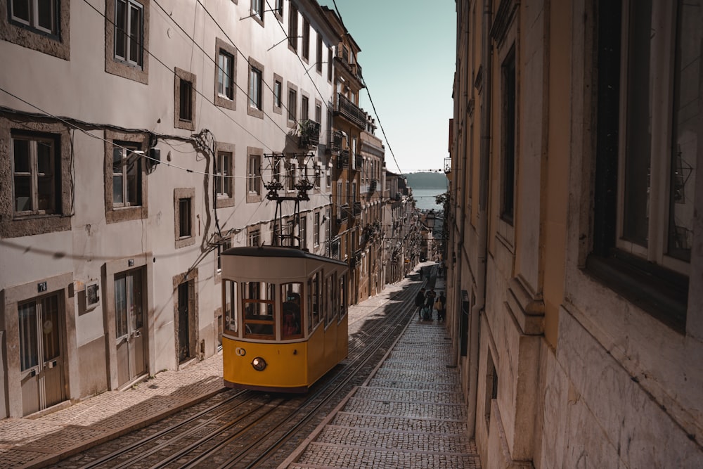 a yellow trolley car traveling down a street next to tall buildings