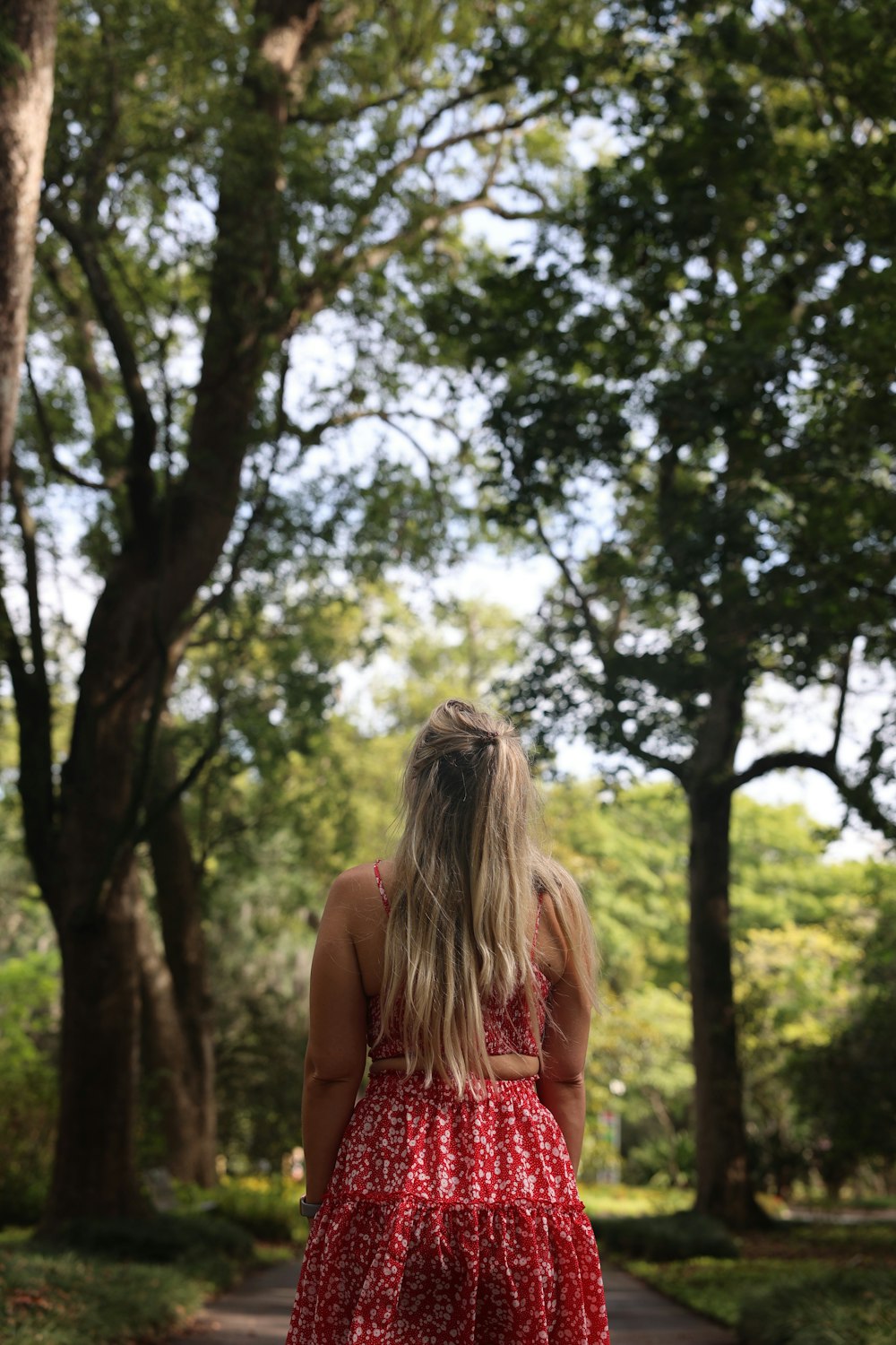 a woman in a red dress is walking down a path