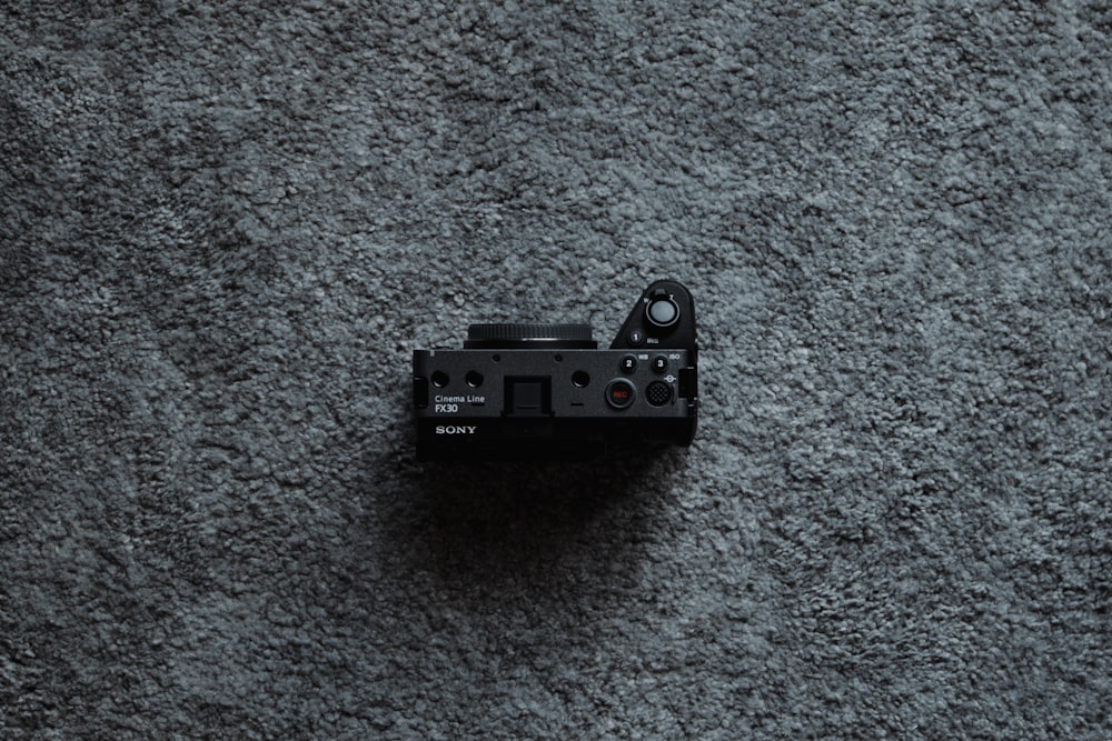 灰色のカーペットの上に座っている黒いカメラ
