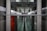 A symmetrical view through a glass window framed with metallic panels featuring a diamond plate pattern. The background appears to be a modern corridor or hallway, with blurred elements suggesting depth and perspective.