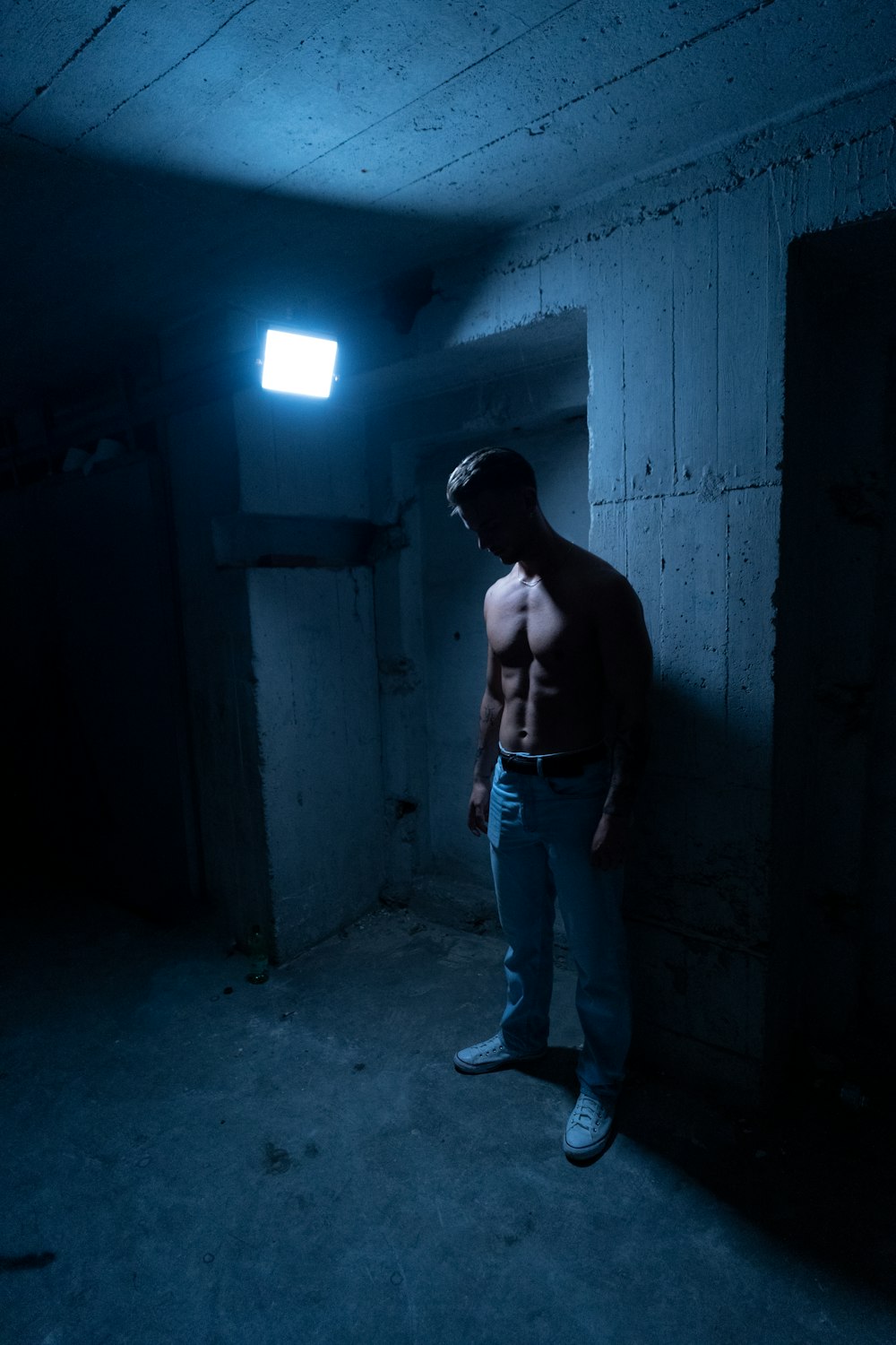 a shirtless man standing in a dark room