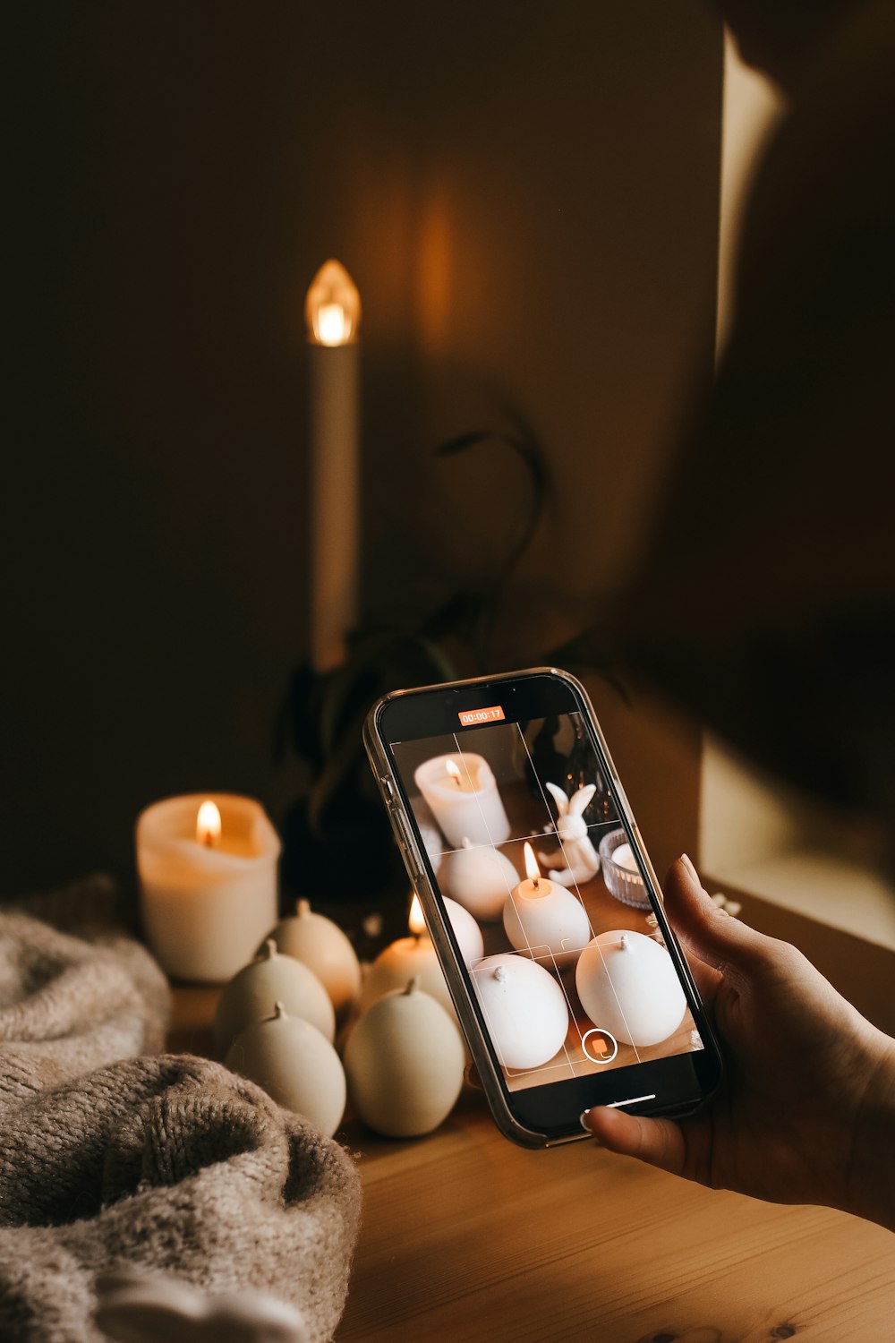 a person holding a cell phone in front of candles