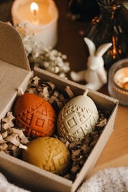 A cozy workshop room with participants focused on creating wax designs on Easter eggs.
