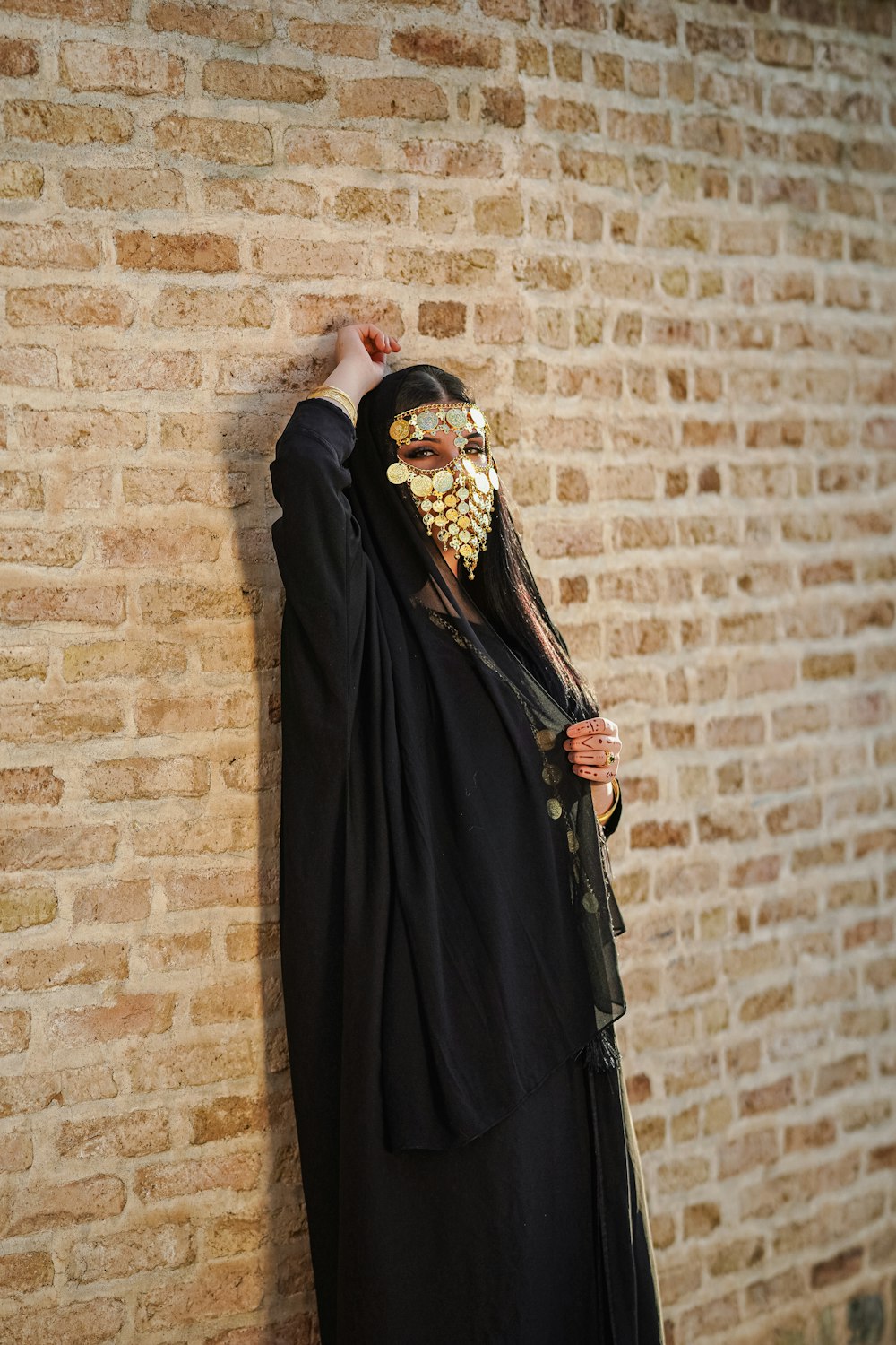a person in a black outfit and a gold mask