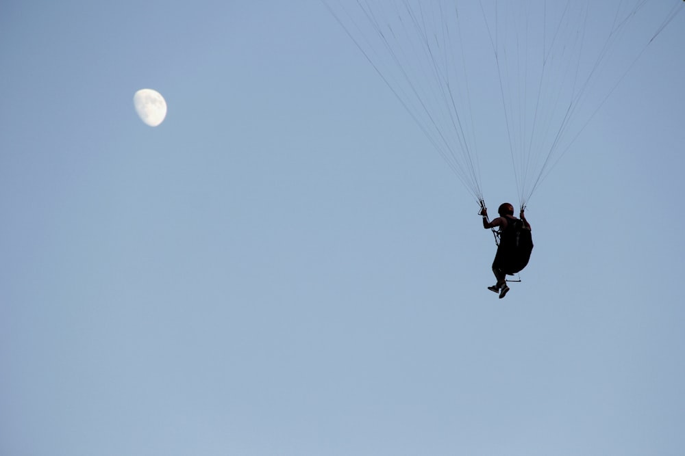 a person is parasailing in the sky with a full moon in the background