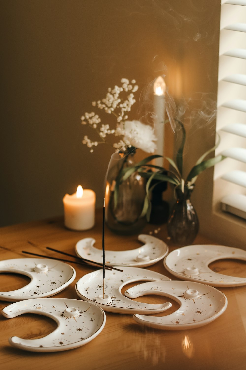 a wooden table topped with white plates and a candle