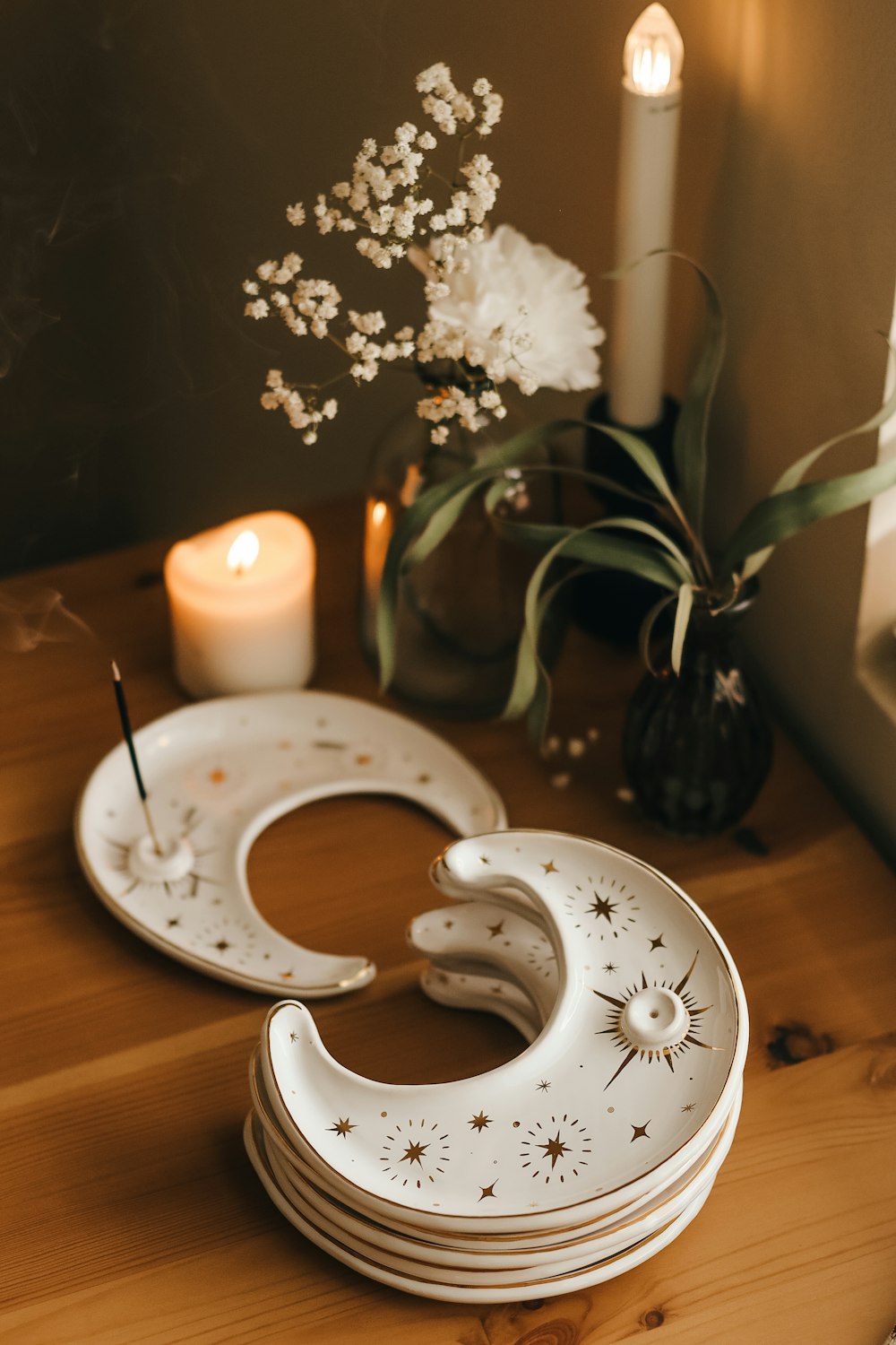 a wooden table topped with plates and a vase filled with flowers