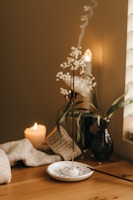 Cozy scene of body care products next to a lit candle and soft fabric