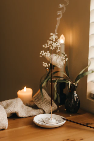 A softly lit scene showing 男香源 essential oils next to a burning candle and fresh eucalyptus leaves.