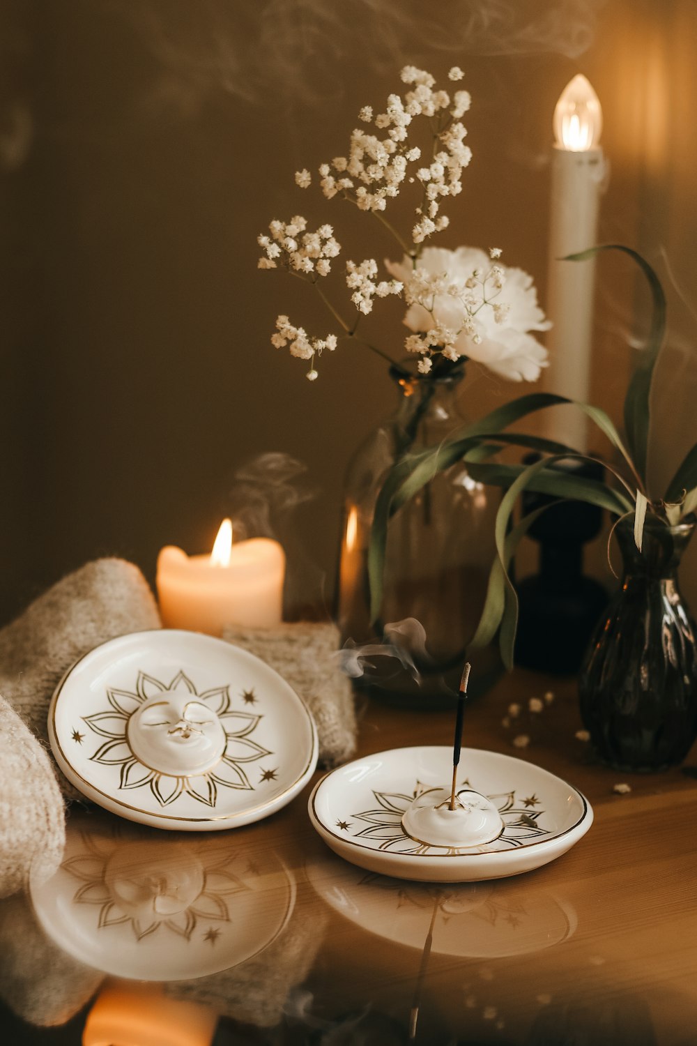 a table topped with two white plates and a vase filled with flowers