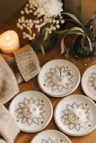 A cozy corner setup with a bright ceramic vase holding fresh flowers beside a stack of handmade plates.