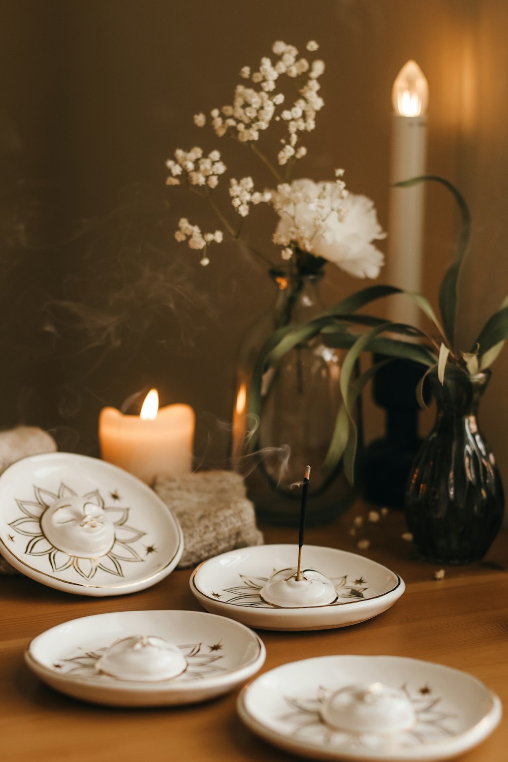 a wooden table topped with white plates and a candle