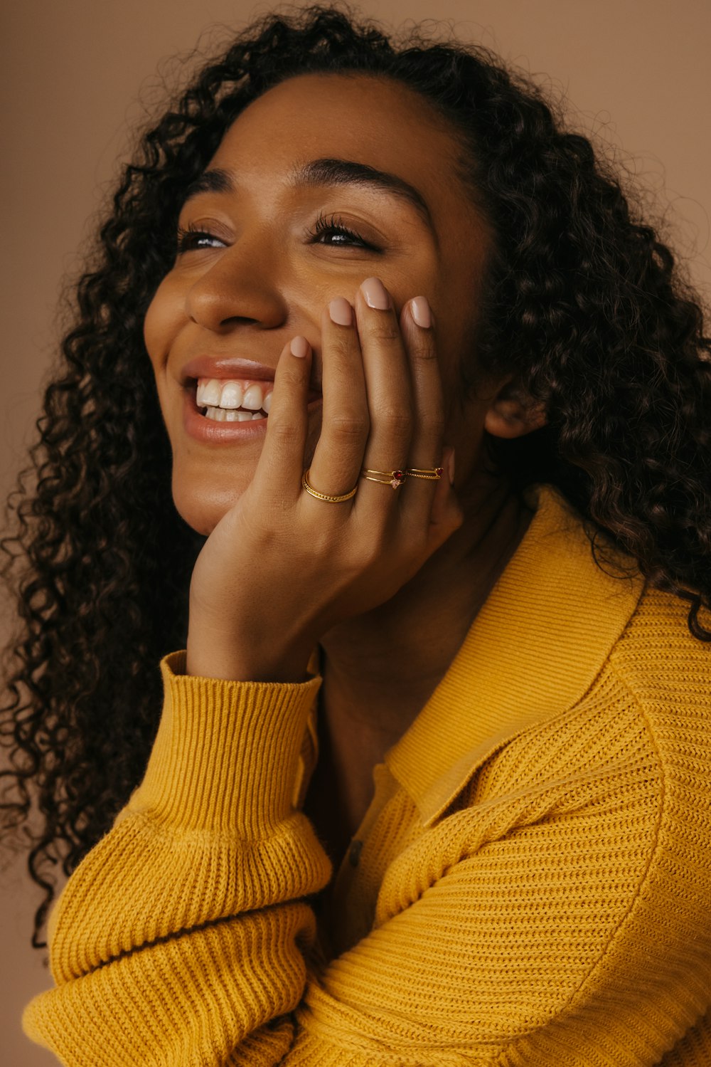 a woman smiling and holding her hands to her face