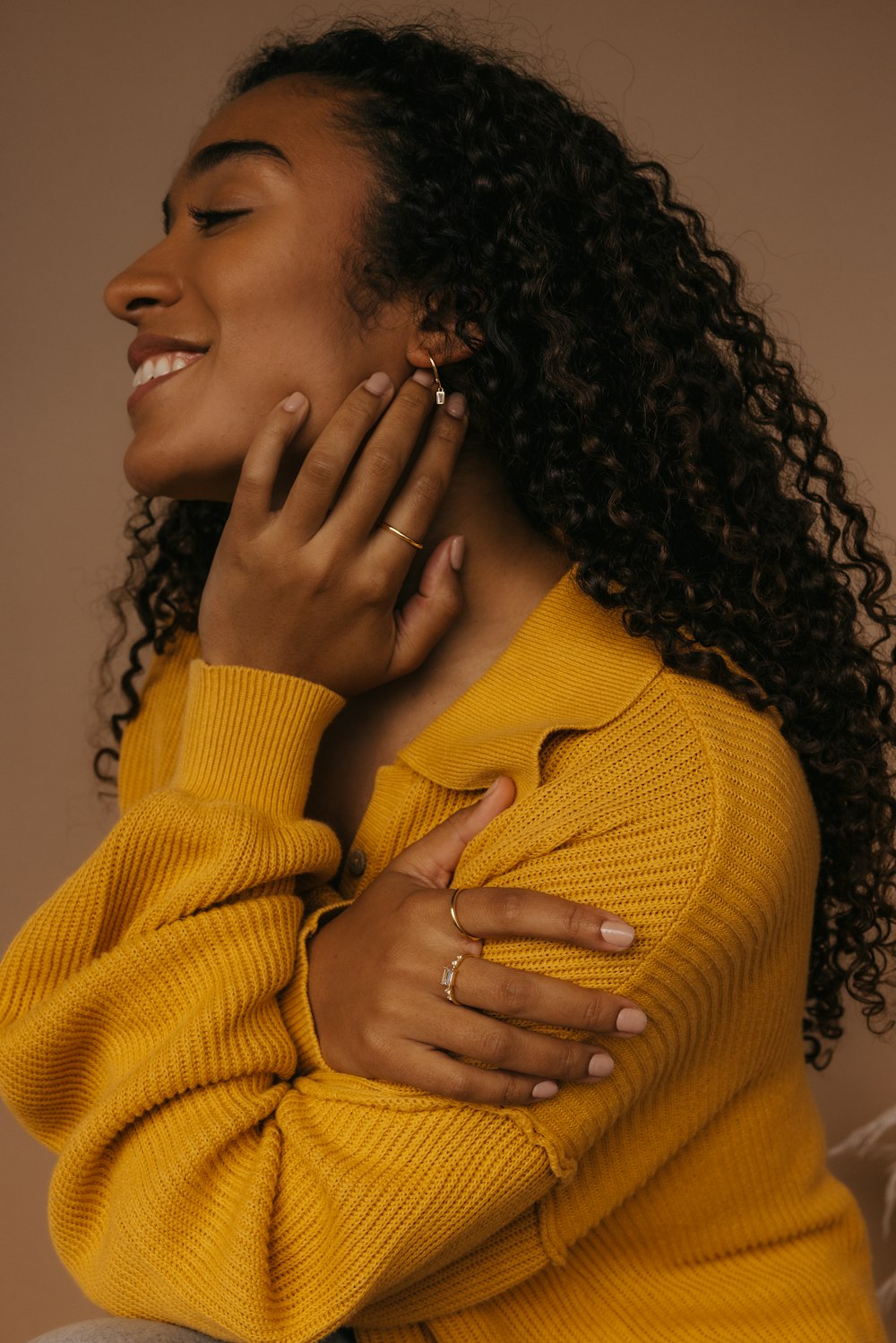 a woman with curly hair wearing a yellow sweater