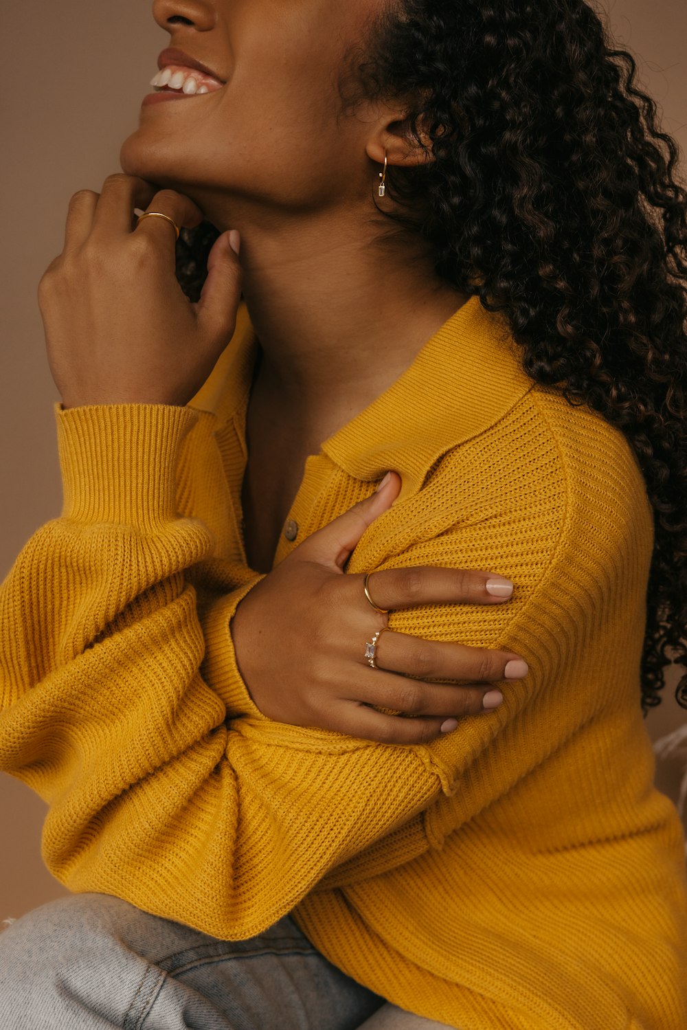 a woman with curly hair wearing a yellow sweater