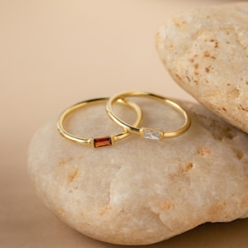 An ivory marble surface adorned with a stack of thin gold rings, capturing refined simplicity.