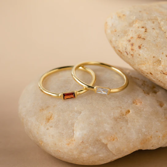 Elegant silver rings stacked artfully on a white marble surface with subtle gold accents in the background