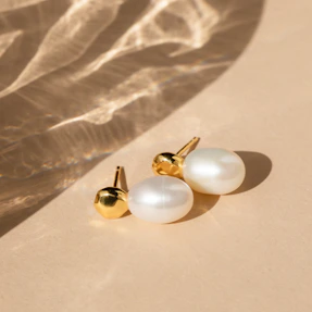 Close-up of elegant silver earrings displayed on a soft beige fabric background.