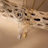 Layered necklaces with subtle pendants against a warm wooden background.