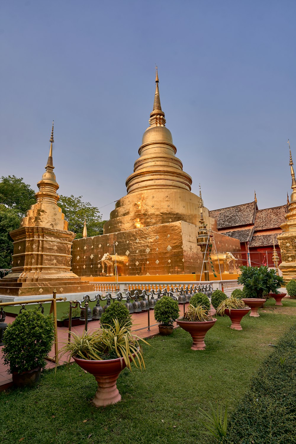 a large golden building with a lot of potted plants in front of it